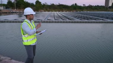 Yüzen güneş çiftliğinde çalışan Asyalı mühendis, yenilenebilir enerji, teknisyen ve yatırımcı güneş panelleri güneş enerjisi kurulumundaki panelleri kontrol ediyor