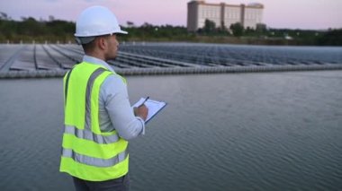 Yüzen güneş çiftliğinde çalışan Asyalı mühendis, yenilenebilir enerji, teknisyen ve yatırımcı güneş panelleri güneş enerjisi kurulumundaki panelleri kontrol ediyor