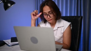 Güzel Asyalı kadın gece evde çalışıyor, şirketten bir sürü iş, eve iş getiriyor, ev konseptinden çalışıyor, sıkı çalışmaktan yorulmuş.