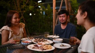 Group of asian people dinning party in the garden of home on holiday, Summer evening garden party celebration with friends