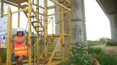 Otoyol köprüsü şantiyesinde çalışan Asyalı bir kadın mühendis inşaat çalışmalarını denetliyor.