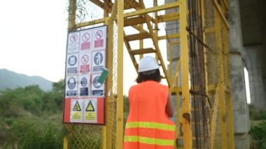 Otoyol köprüsü şantiyesinde çalışan Asyalı bir kadın mühendis inşaat çalışmalarını denetliyor.