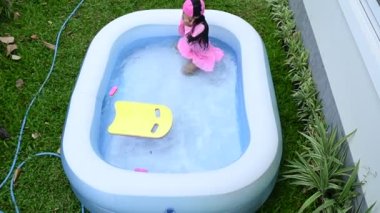 Asian little girl swimming inflatable pool at home with fun