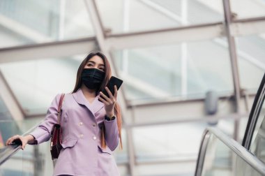 Parktaki güzel Asyalı iş kadınının portresi Covid-19 'u korumak için maske tak.