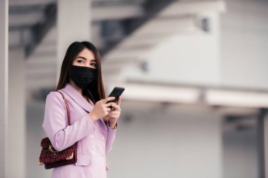 Parktaki güzel Asyalı iş kadınının portresi Covid-19 'u korumak için maske tak.