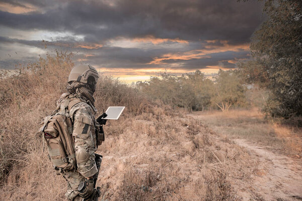 Солдат с помощью карты на планшете для ориентации в лесу
