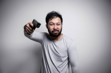 Asian handsome man angry on white background,Portrait of young Stress male concept,Hold gun in hand