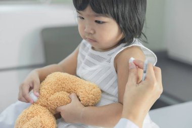 Solunumunu ve kalbini kontrol etmek için steteskop kullanan Asyalı bir doktor, Taylandlı çocukların sağlığını kontrol ediyor.