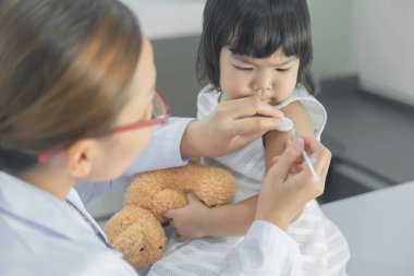 Solunumunu ve kalbini kontrol etmek için steteskop kullanan Asyalı bir doktor, Taylandlı çocukların sağlığını kontrol ediyor.