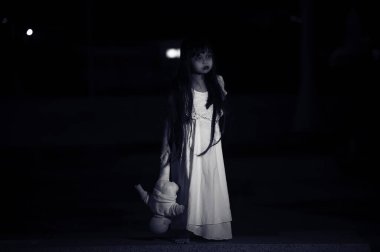 Gece üzgün çocuk hayaleti, Cadılar Bayramı festivali konsepti, 13. Cuma, korku filmi sahnesi, oyuncak bebeği olan bir kız.