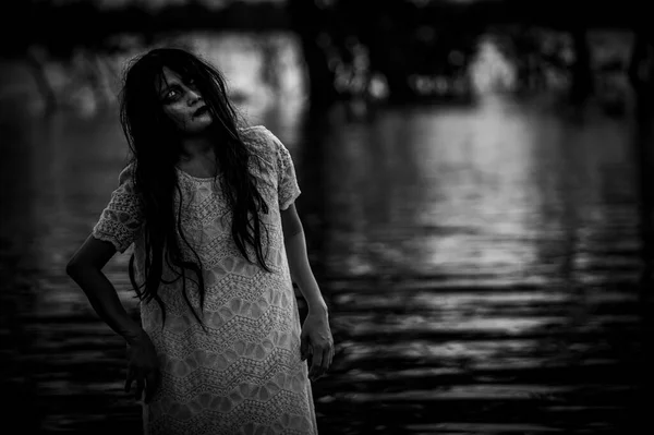 Portrait of asian woman make up ghost face at the swamp,Horror in water scene,Scary at river,Halloween poster,Thailand people