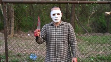 Asian handsome man wear clown mask with knife at the night scene, Halloween festival concept, Horror scary photo of a killer in orange cloth