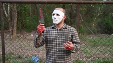 Asian handsome man wear clown mask with knife at the night scene, Halloween festival concept, Horror scary photo of a killer in orange cloth