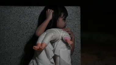 Sad child ghost at night. Halloween Festival concept. Friday 13th. Horror movie scene. A girl with doll