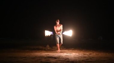Male fire dancer perform fire show on the beach at night