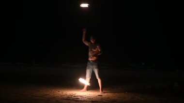 Male fire dancer perform fire show on the beach at night