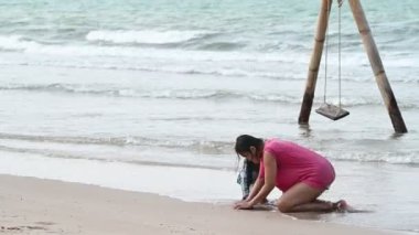 Mother and daughter play sand at side sea beach on the sunset, Thailane people, Relax time