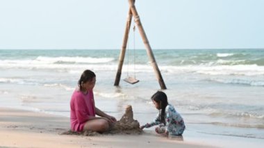 Mother and daughter play sand at side sea beach on the sunset, Thailane people, Relax time