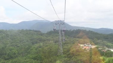 Dağlardaki yeşil ormanın üzerinden geçen kablo araba.