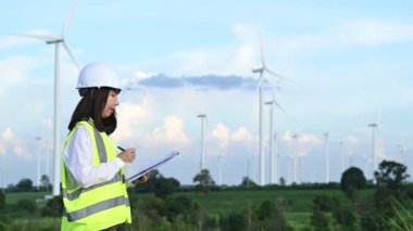 Tayland 'daki dağda rüzgar türbini çiftliği elektrik jeneratörü istasyonunda çalışan ve raporu tutan kadın mühendis.