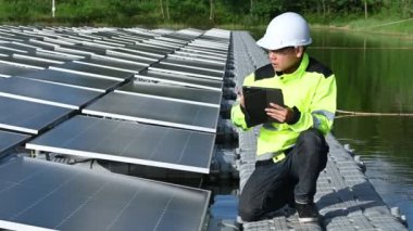 Yüzen güneş enerjisi santralinde çalışan Asyalı mühendis, yenilenebilir enerji, teknisyen ve yatırımcı güneş panelleri güneş enerjisi kurulumundaki panelleri kontrol ediyor