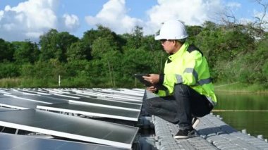 Yüzen güneş enerjisi santralinde çalışan Asyalı mühendis, yenilenebilir enerji, teknisyen ve yatırımcı güneş panelleri güneş enerjisi kurulumundaki panelleri kontrol ediyor