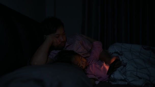 父と娘は寝室でベッドで寝る 電話で漫画を見る 父の日の概念 シングルお父さん 寝る前に話を聞く — ストック動画