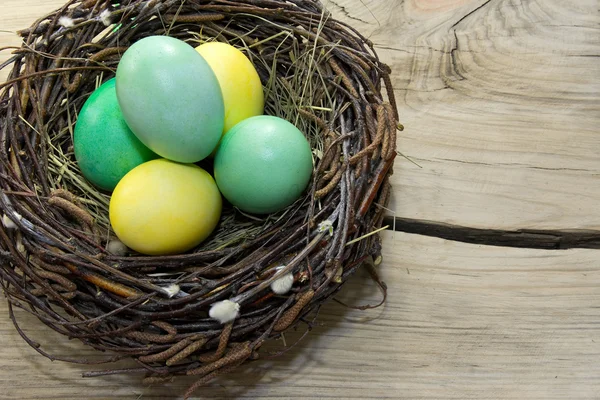 Ovos de Páscoa no ninho no fundo de madeira — Fotografia de Stock