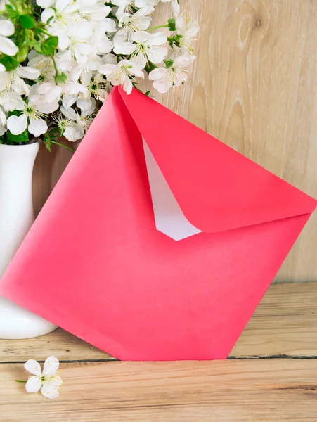Roter Umschlag und weiße Vase mit Kirschblüten auf hölzernem Hintergrund — Stockfoto