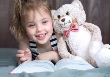 Elinde oyuncakla kitap okuyan kız çocuğu. Mutlu çocuklar öğreniyor. Bebek eğitimi konsepti. Küçük kadın portresi. Yakın plan..