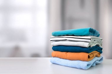 Renkli giysiler yığını. Boş masa arkaplanındaki giysi yığını. Çamaşır ve ev işleri..