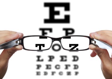 önünde göz testi, ellerinde gözlük