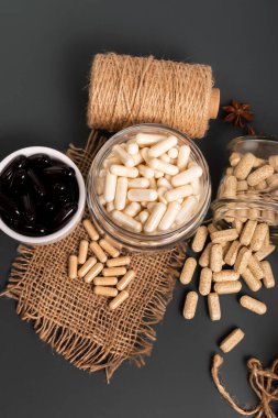 Koyu siyah arka planda kırsal tarzda tablet, hap ve kapsüller şeklinde gıda takviyeleri. İnsan bağışıklık sistemini virüslerden ve bakterilerden korumak için besin takviyeleri. Balık yağı, magnezyum. Glüten ve laktozsuz vitamin ve mineral yok..