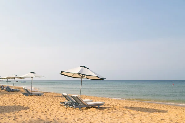 带着伞在美丽的海滨沙滩日光浴浴床 — 图库照片