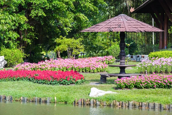 Fiore e albero nel giardino decorato con un tavolo in legno arrotondato — Foto Stock