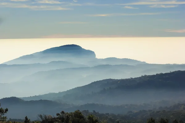 霧と太陽の光の中で山の層 — ストック写真