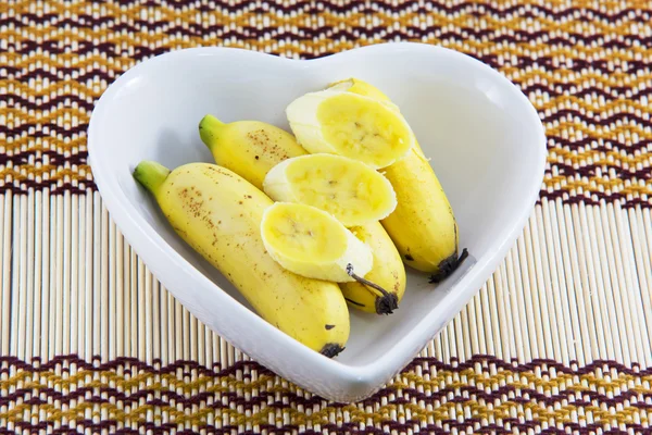 Plátanos frescos en un tazón en forma de corazón — Foto de Stock