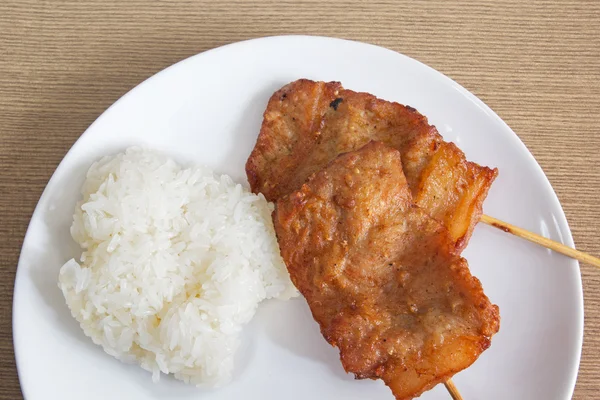 Barbacoa de cerdo a la parrilla con arroz pegajoso en un plato blanco — Foto de Stock