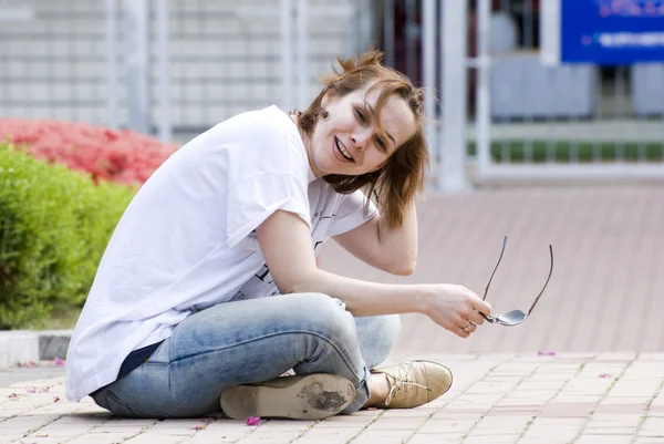 Young girl of the European appearance sitting on the sidewalk . — Stok fotoğraf