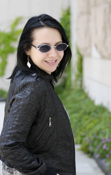 Young beautiful girl of the European appearance in sunglasses and leather jacket. — Stock Photo, Image