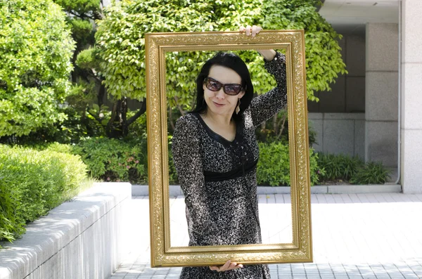 Giovane ragazza dell'apparizione europea in occhiali da sole in posa con una cornice . — Foto Stock