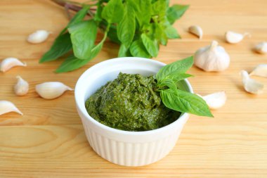 Beyaz kâsede nefis ev yapımı taze fesleğen pesto sosu ve arka planda içeriği var.