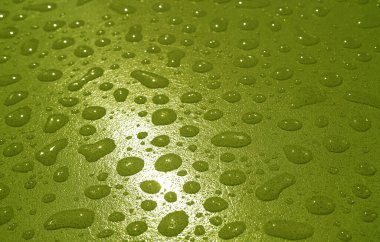 Yağan zeytin yeşili yağmurdan sonra akrilik masanın üstündeki su damlacıklarının yakınlaştırılması