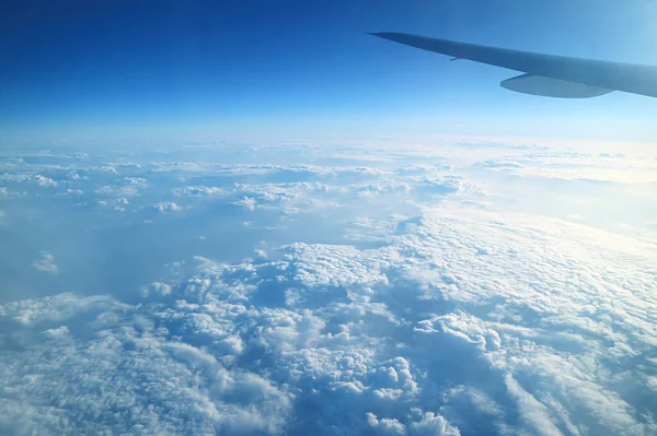 飛行中の飛行機の窓からの鮮やかな青空とふわふわの白い雲の景色に飛行機の翼 — ストック写真