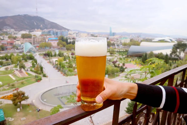 Ręczne Trzymanie Szklanki Piwa Balkonie Rozmazanym Widokiem Miasto Tle — Zdjęcie stockowe