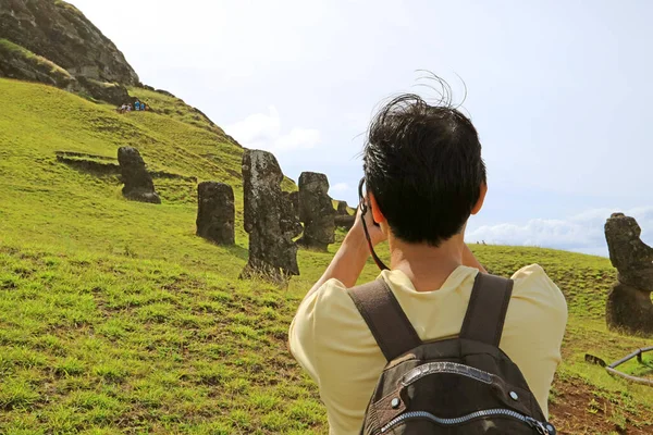 游客拍摄散落在智利伊斯特岛上原莫埃采石场拉诺卡库火山上的莫埃雕像 — 图库照片