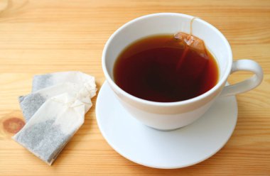 Tahta masada çay poşetleriyle bir fincan sıcak çay.