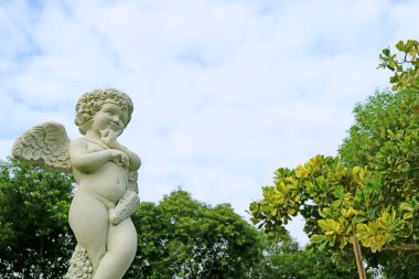Bahçedeki sevimli aşk tanrısı heykelini pofuduk bulutlu gökyüzüne yaklaştır.