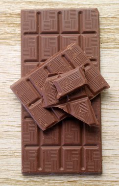 Tahta arka planda izole edilmiş çikolata parçalarının üst görünümü