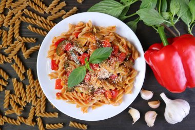 Plate of Delectable Whole Wheat Fusilli Pasta in Tomato Sauce with Its Ingredients Scattered Around